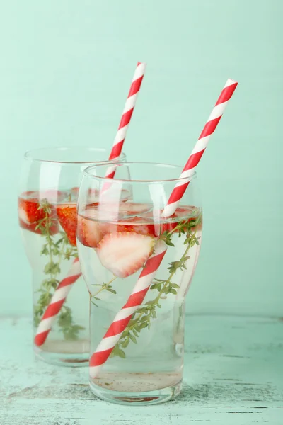 Tasty cool beverage with strawberries and thyme, on wooden background