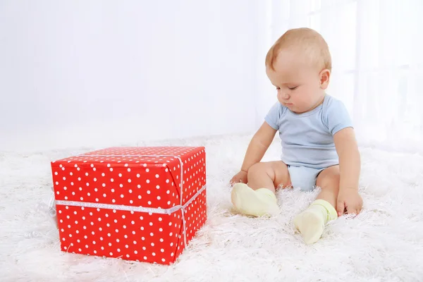 Söt pojke med nuvarande låda på mattan i rummet — Stockfoto