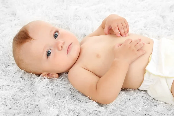 Cute baby boy lying on carpet in room — Stock Photo, Image