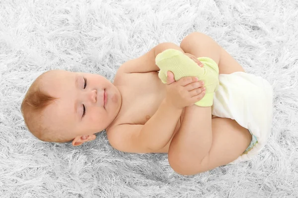 Schattige babyjongen liggend op tapijt in kamer — Stockfoto