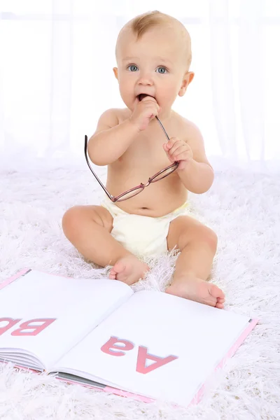 Lindo bebé con libro sobre alfombra en la habitación — Foto de Stock