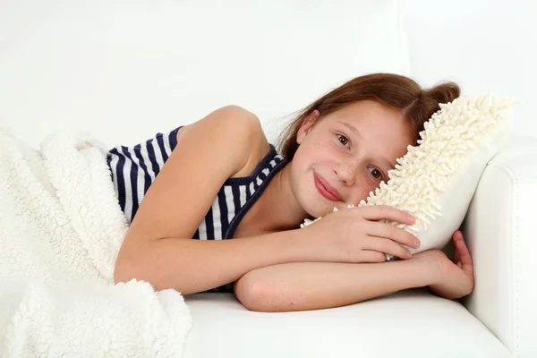 Beautiful little girl lying on sofa in room — Stock Photo, Image