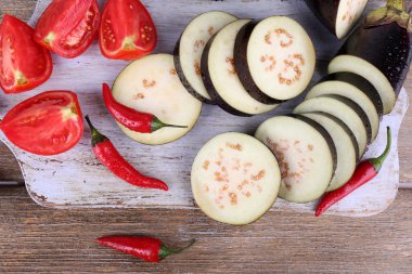 ahşap zemin üzerinde kesme tahtası üzerinde serin biber ve domates ile doğranmış patlıcan
