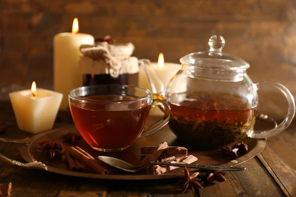 Композиция с чаем в чашке и чайник и свечи на столе, на деревянном фоне — стоковое фото