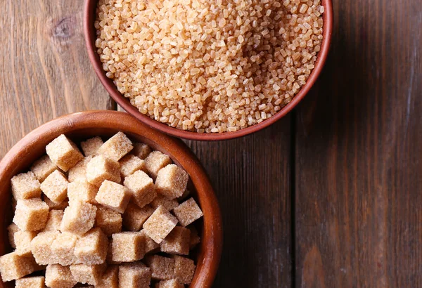Кубики коричневого сахара и хрустальный сахар в миске на деревянном фоне — стоковое фото