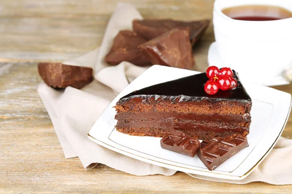 Choklad tårta med färska bär på plattan, färg trä bakgrund — Stockfoto