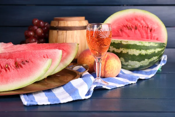 Composizione di anguria matura, frutta, vino rosa in vetro e botte di legno su fondo di legno — Foto Stock