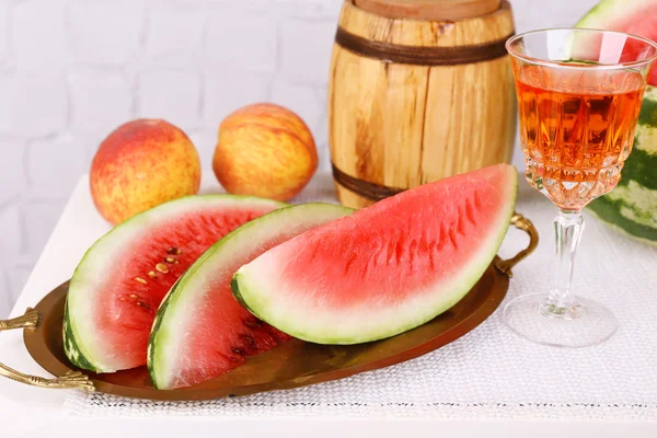 Composition de pastèque mûre, fruits, vin rose en verre et tonneau en bois sur table en bois de couleur, sur fond clair — Photo