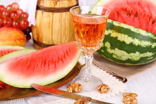 Sammansättningen av mogen vattenmelon, frukter, rosa vin i glas och trä fat på färg träbord, på ljus bakgrund — Stockfoto