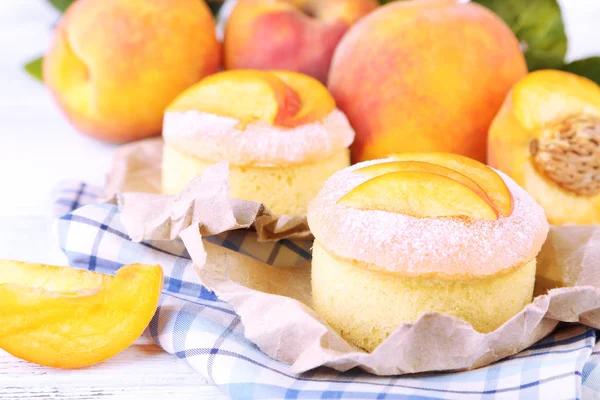 Tasty mini cakes with fresh peach, on wooden table — Stock Photo, Image