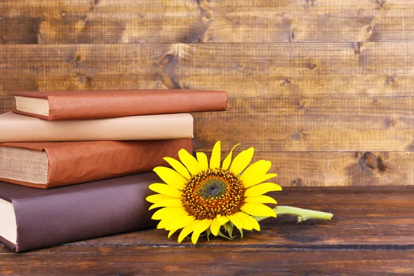 Libros y girasol sobre mesa de madera —  Fotos de Stock