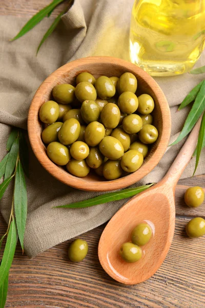 Green olives in bowl with leaves on table close-up — Stock Photo, Image