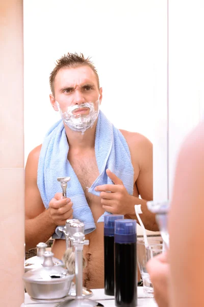 Jeune homme rasant sa barbe dans la salle de bain — Photo