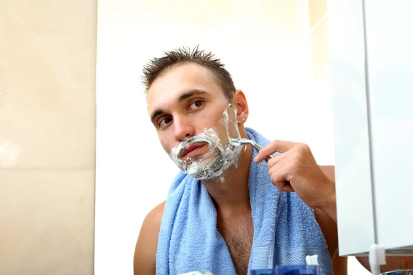 Mladý muž holení jeho vousy v koupelně — Stock fotografie