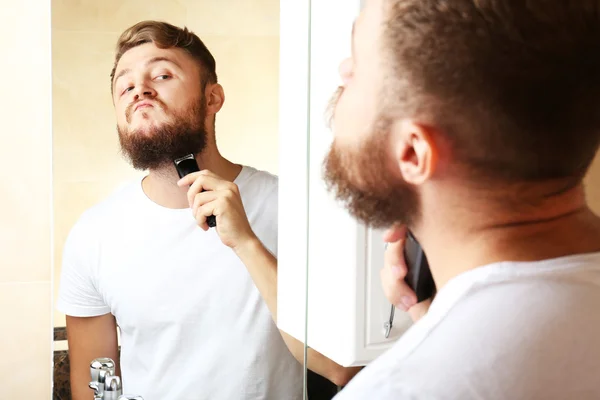 Jeune homme rasant sa barbe dans la salle de bain — Photo