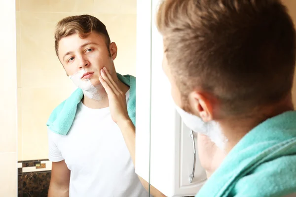 Jeune homme rasant sa barbe dans la salle de bain — Photo