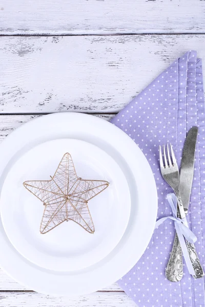 Assiette blanche, fourchette, couteau et décoration de Noël sur serviette à pois lilas sur fond en bois — Photo