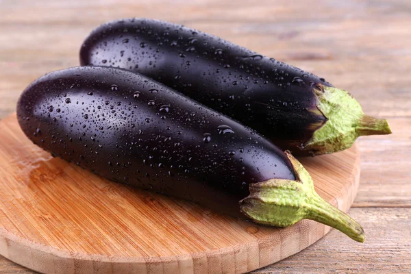 Aubergine på runda skärbräda på trä bakgrund — Stockfoto