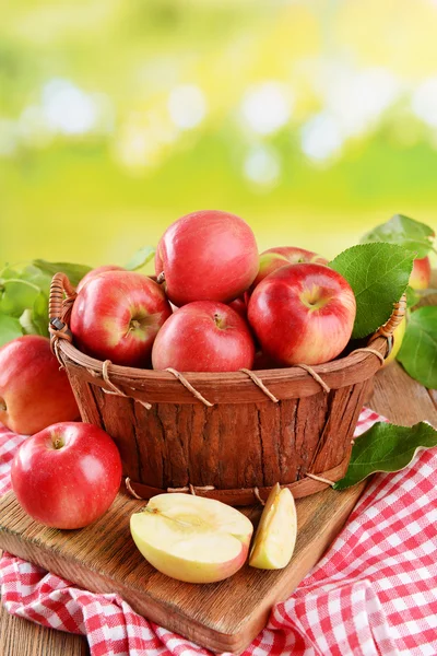 Manzanas dulces en canasta de madera sobre mesa sobre fondo brillante — Foto de Stock