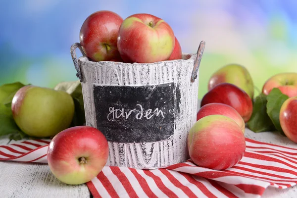 Sladká jablka v koši na stole na světlé pozadí — Stock fotografie