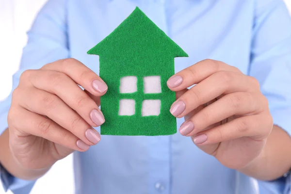 Frau hält Papierhaus auf hellem Hintergrund — Stockfoto