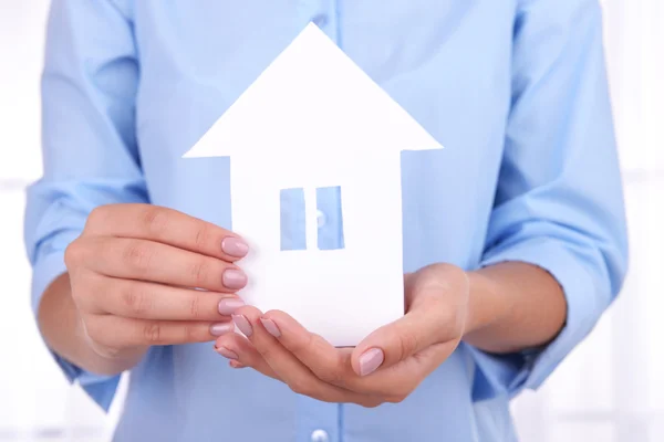 Woman hands holding paper house on light background — Stock Photo, Image