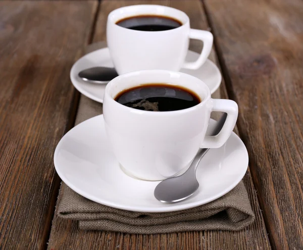 Two cups of coffee on sackcloth napkin on wooden background — Stock Photo, Image