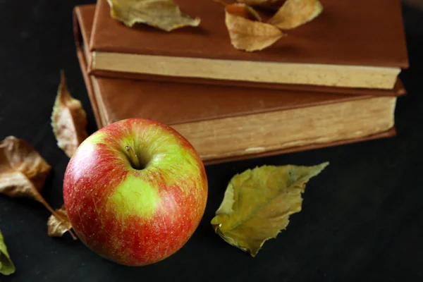 Jabłko z książek i suche liście — Zdjęcie stockowe
