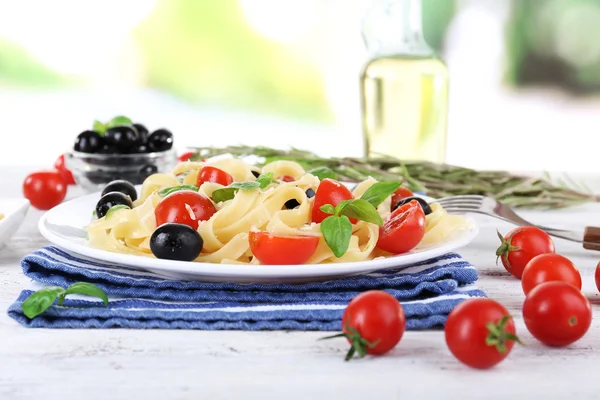 Spaghetti med tomater, oliver och basilika blad på plattan på servett på trä bakgrund — Stockfoto