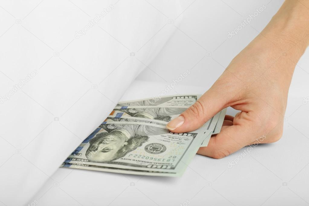Woman hiding money under pillow at home Stock Photo by ©belchonock 53954101
