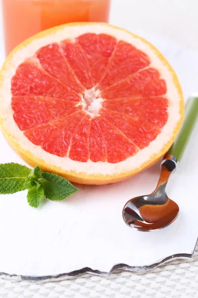 Metade de toranja e colher em tábua de madeira no fundo claro — Fotografia de Stock