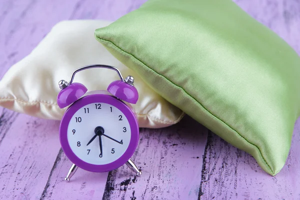 Plastic clock on a silk pillows — Stock Photo, Image