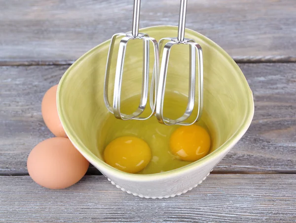 Kochen: Eier mit Elektromixer in Schüssel auf Holztisch schlagen — Stockfoto