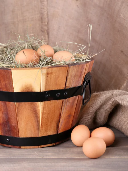 Nagy kerek kosár, szárított fű és friss tojás a zsákolás a háttérben — Stock Fotó