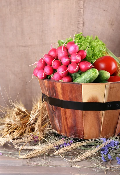 Big round wooden basket with vegetables and ears on sacking background — Stock Photo, Image