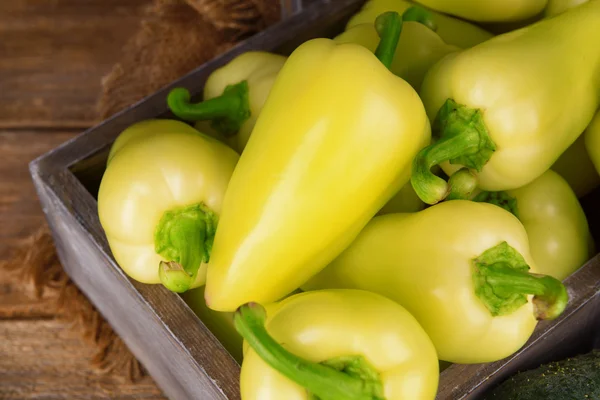 Yellow peppers in crate with sackcloth on table close up — Stock Photo, Image