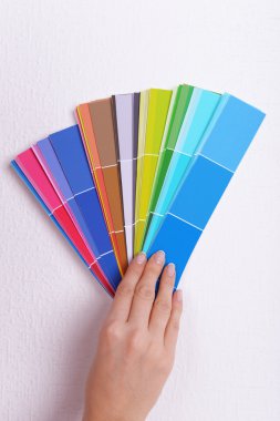 Duvarın rengini odadaki kumaşlardan seçen kadın