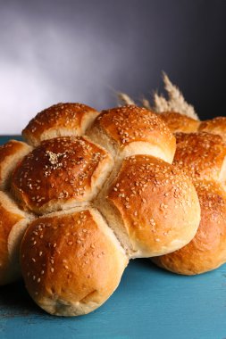 Gri arka plan üzerinde renkli ahşap masa üstünde susam ile lezzetli çörekler