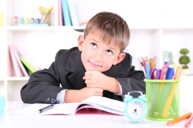 школяр, сидячи на столі в класі