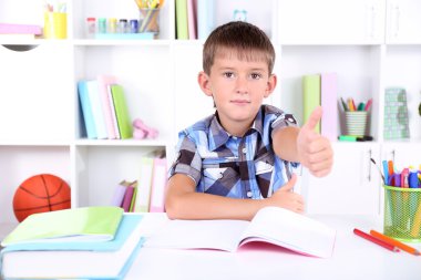 школяр, сидячи на столі в класі