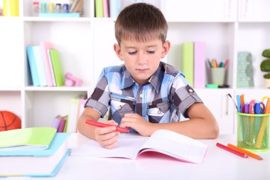 школяр, сидячи на столі в класі