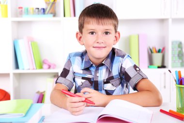 школяр, сидячи на столі в класі