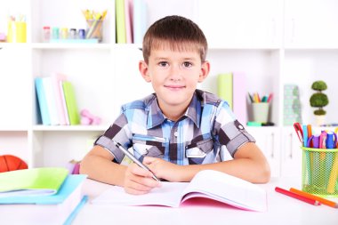 школяр, сидячи на столі в класі