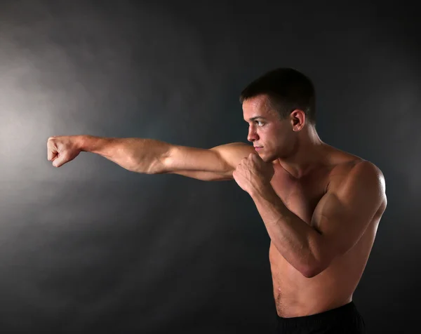 Beau jeune sportif musclé boxe sur fond sombre — Photo