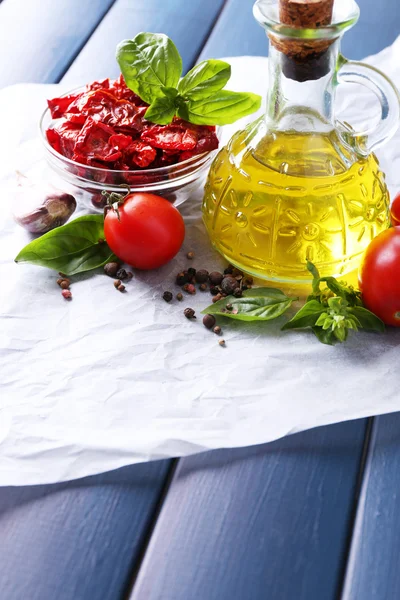 Güneş cam, cam şişe zeytinyağı, kurutulmuş domates, fesleğen yaprakları renk ahşap arka plan üzerinde — Stok fotoğraf