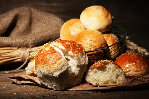 美味面包芝麻糊在篮子里，木质的背景 — 图库照片