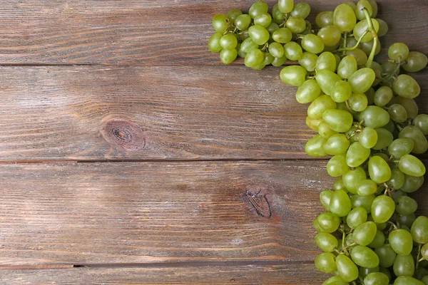 Bunch of ripe grapes on brown wooden background — Stock Photo, Image