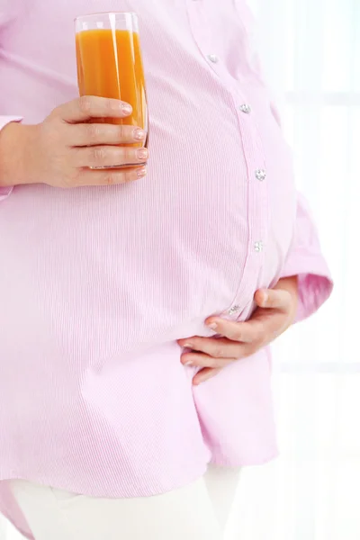 Young pregnant woman holding glass of juice on light background — Stock Photo, Image