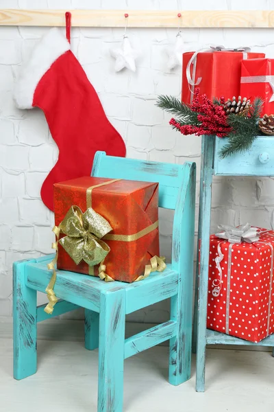 Cadeaux de Noël sur chaise bleue et bibliothèque sur fond de mur de briques — Photo