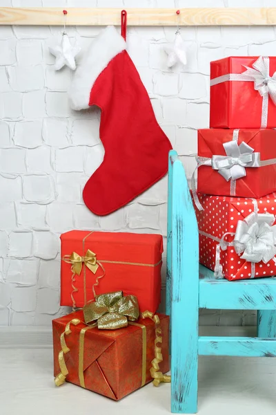 Kerstcadeautjes op blauwe stoel op bakstenen muur achtergrond — Stockfoto